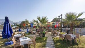 An outdoor seating area with tables and chairs, a pathway, and flags. - Aslan City Hotel (Alanya)