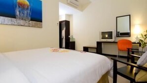 A hotel room with a bed, a desk, a chair, a TV, and a painting on the wall. - iShine Hotel (Pekanbaru)