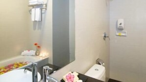 A bathroom with a bathtub, a toilet, a sink, and a mirror. - iShine Hotel (Pekanbaru)