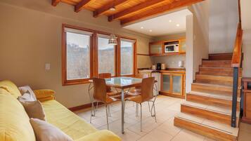 A modern interior with a dining area, kitchen, and a staircase.