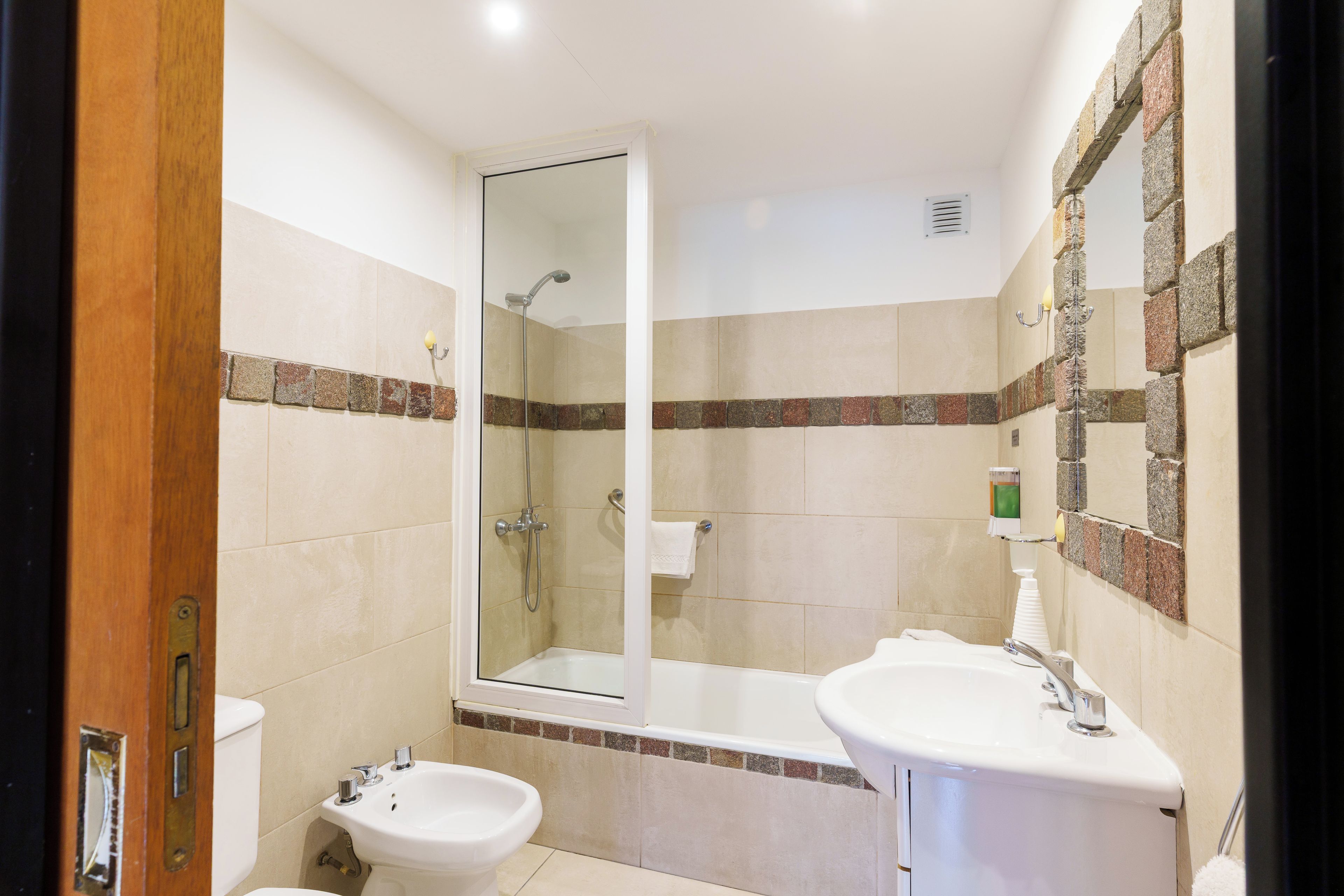 A bathroom with a shower, two sinks, and a toilet.