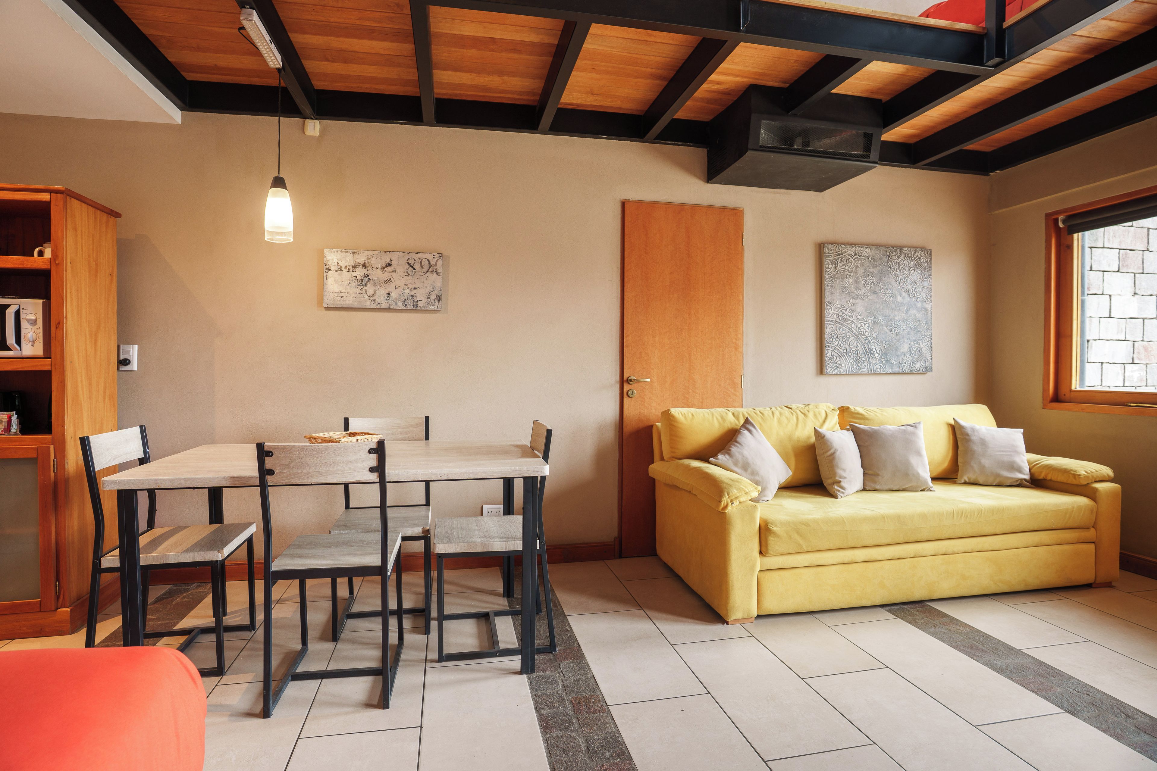 Quarto com mesa de jantar, cadeiras, sofá e janela.