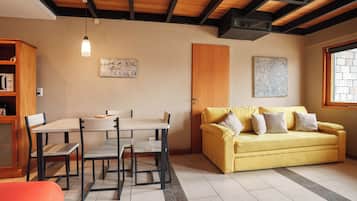 Quarto com mesa de jantar, cadeiras, sofá e janela.