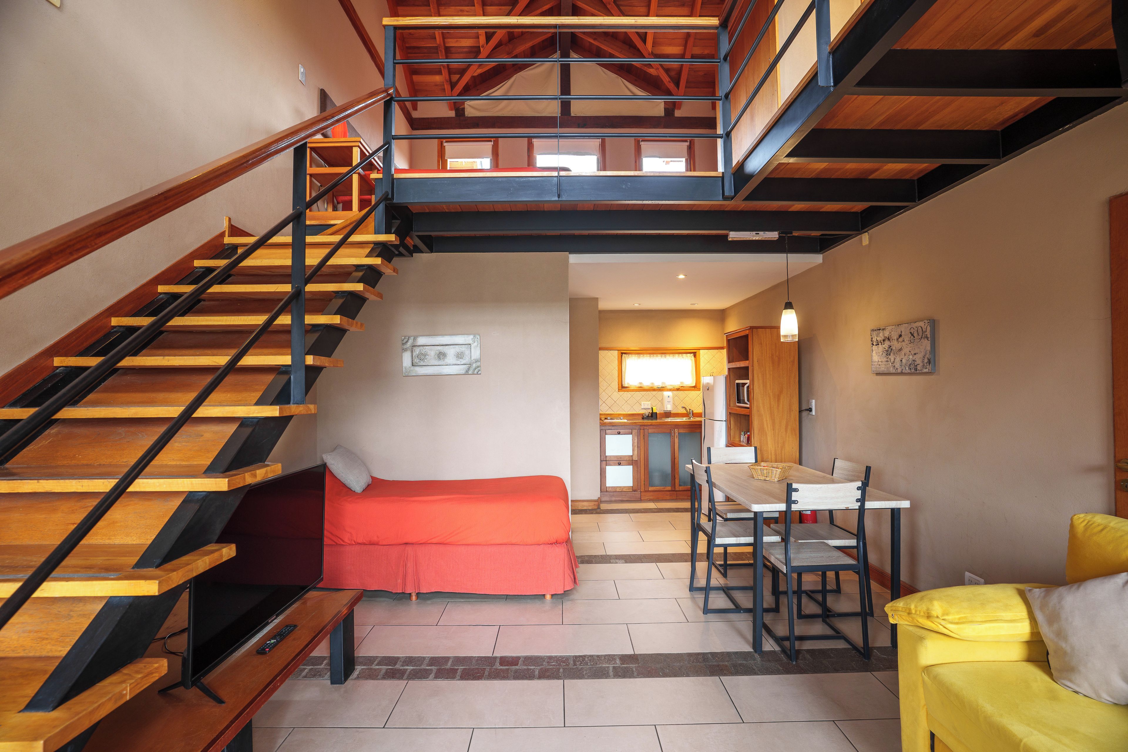 A multi-level interior with a staircase, a sofa, a dining table, and a kitchen area.