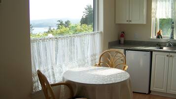 A small kitchen with a view of the outdoors, a table with a chair, and a window with a view.