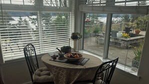 Un comedor con una mesa redonda, dos sillas y vistas al exterior a través de amplios ventanales.
