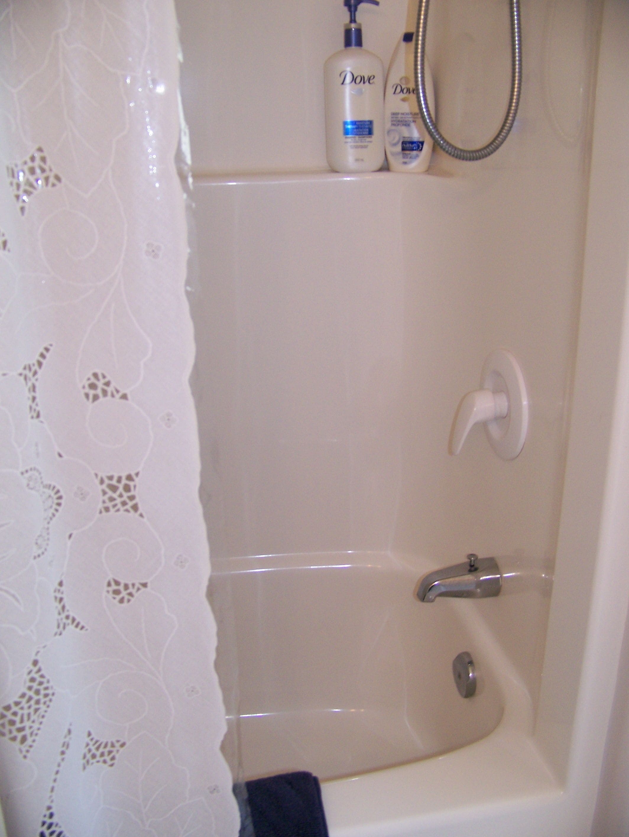 A bathroom with a shower, a towel rack, and toiletries on the wall.