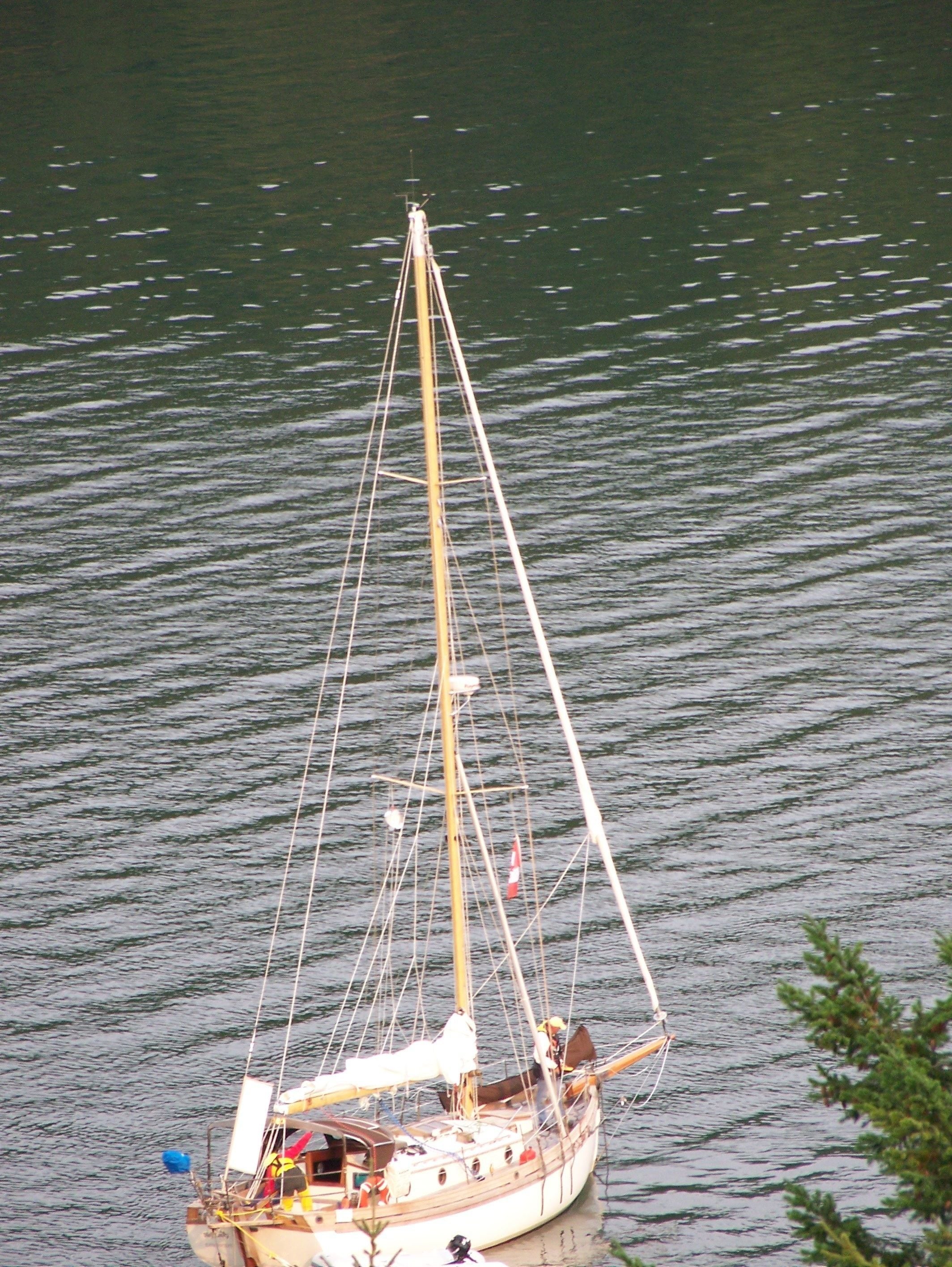 Un voilier à mât élevé et doté de nombreuses voiles, ancré dans une eau calme.