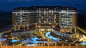 Un hotel de varios pisos con fachada curva, piscina al aire libre y un patio ajardinado.