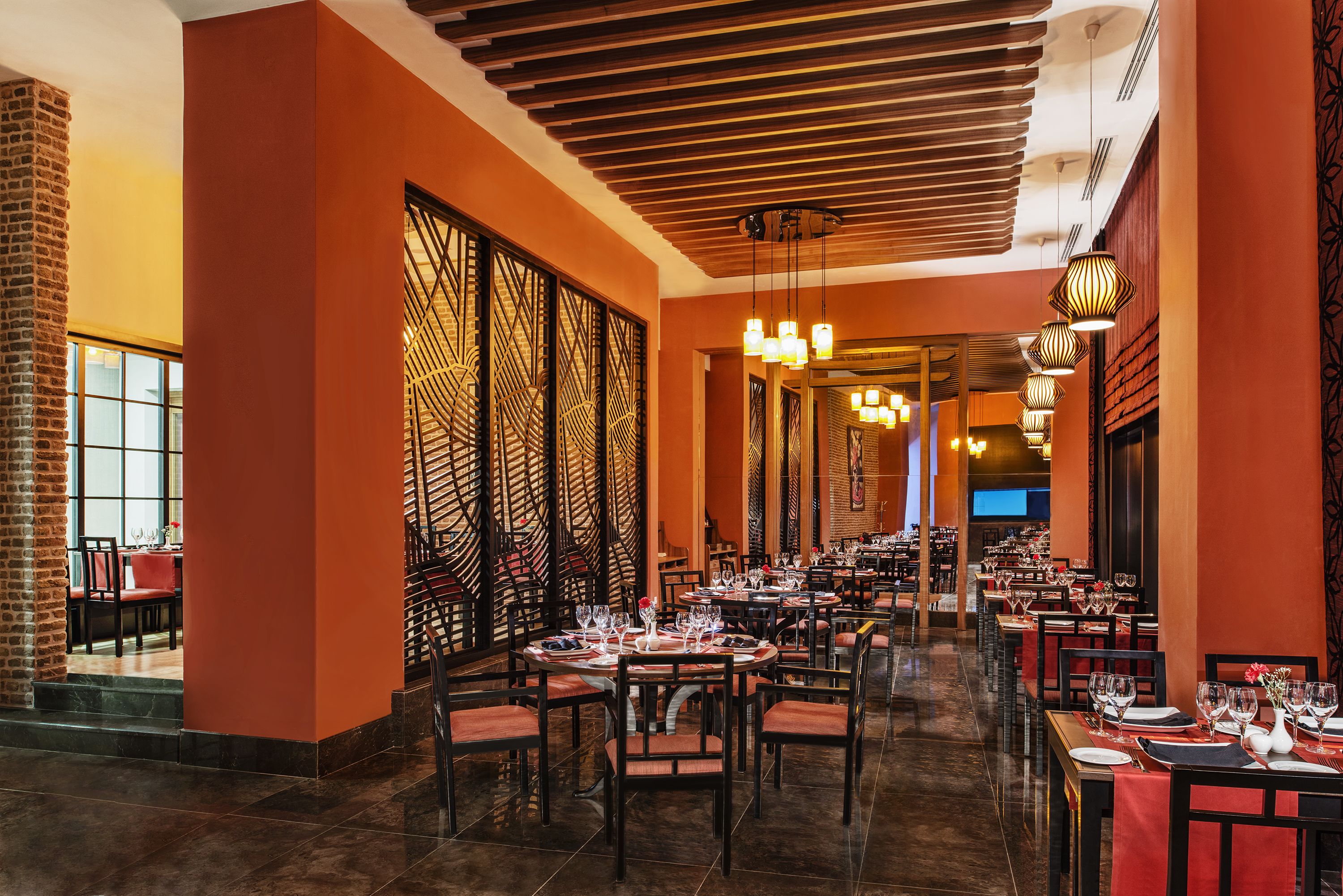 Een restaurant met meerdere tafels voor diners, met een modern interieur met houten balken en een warme kleurenschaal.