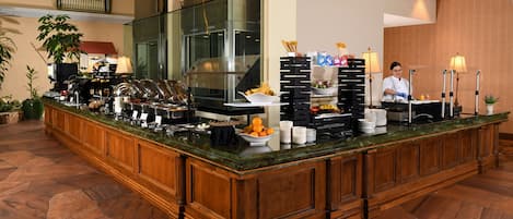 Un buffet proposant une variété de plats et un chef qui prépare les aliments.