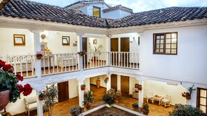 A courtyard with a tiled roof, white walls, and multiple balconies. There are potted plants and a small table with chairs. - Hotel & Spa Getsemaní (Villa de Leyva)