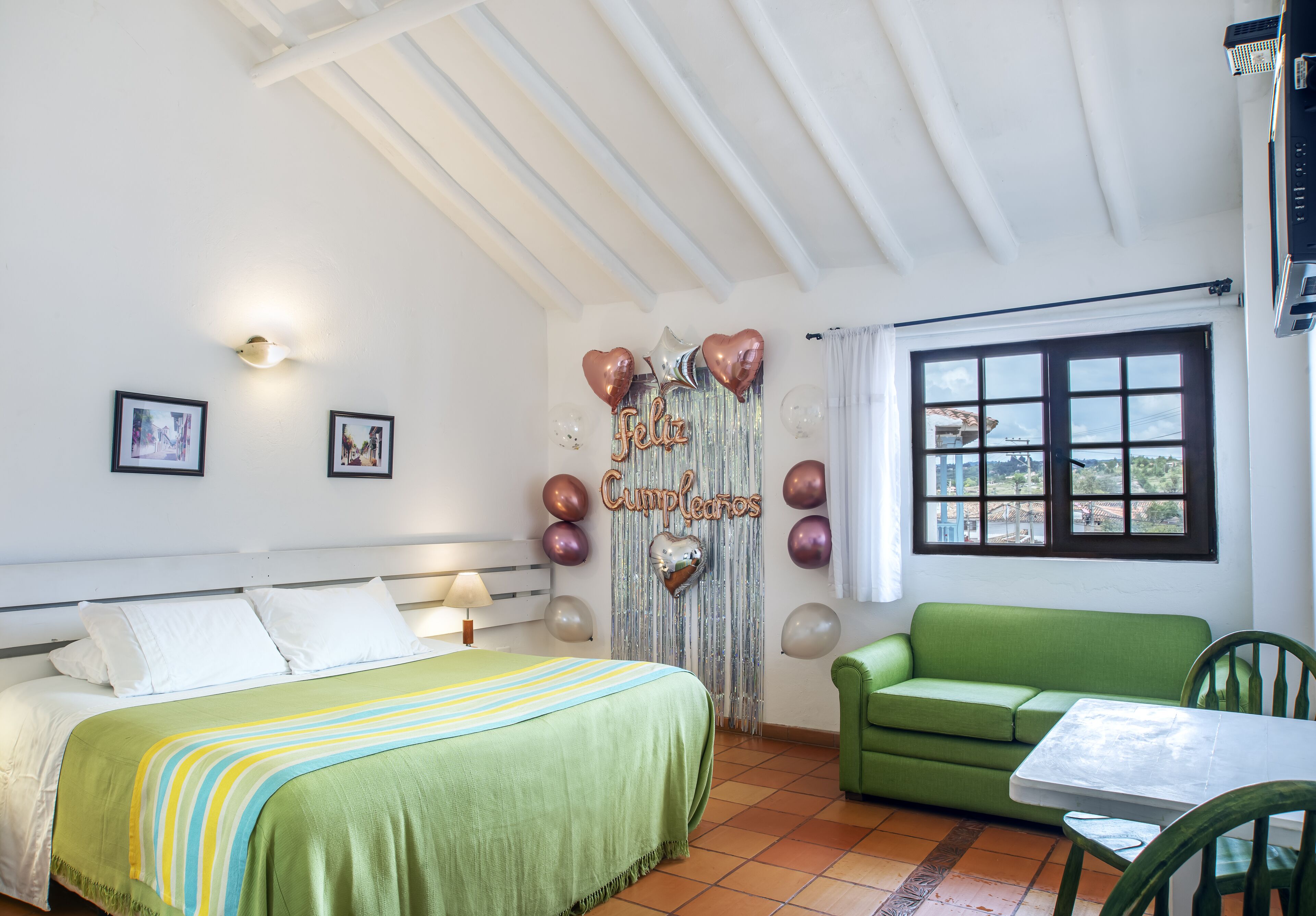 Un dormitorio con cama, sofá verde y una mesa.
