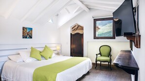 Une chambre à coucher avec un lit, une chaise, un téléviseur et un tableau accroché au mur.