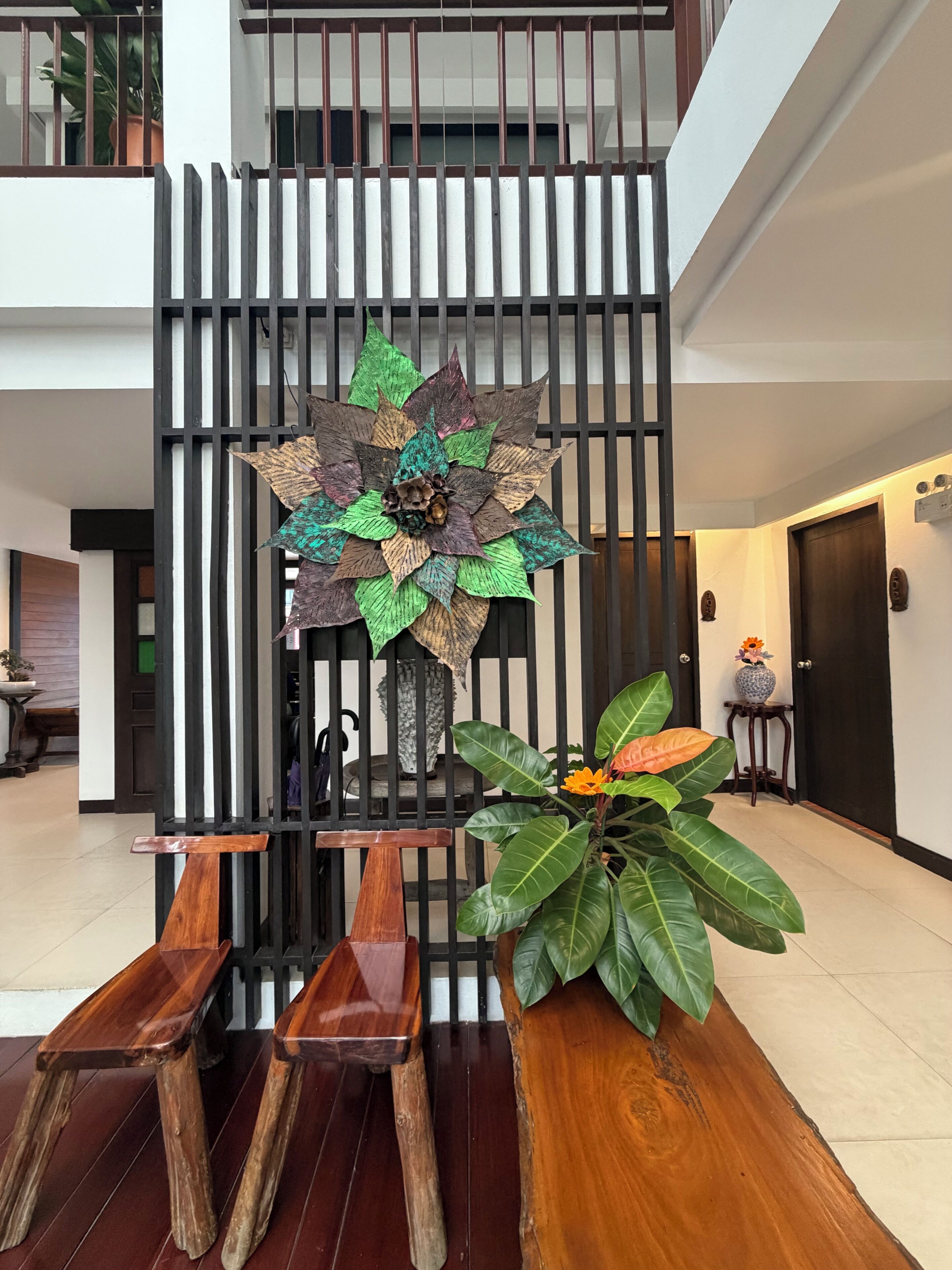 Un interior modern amb un panell decoratiu, una banca de fusta i una planta en test.