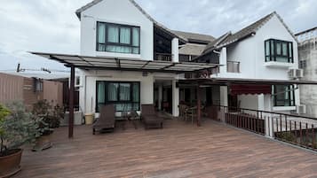 Una casa de dos pisos con un patio cubierto y mobiliario exterior.