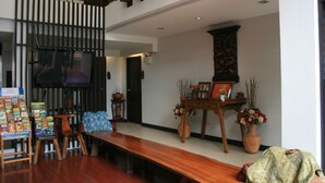A spacious living area with a wooden bench, a television, and a decorative vase with flowers. - Baan Ing Ping (Chiang Mai)
