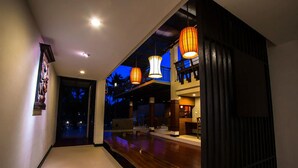 A hallway with wooden flooring, recessed lighting, and hanging lantern-style lights. - Baan Ing Ping (Chiang Mai)