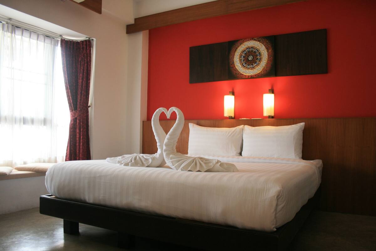 A neatly made bed with white linens and two heart-shaped pillows.