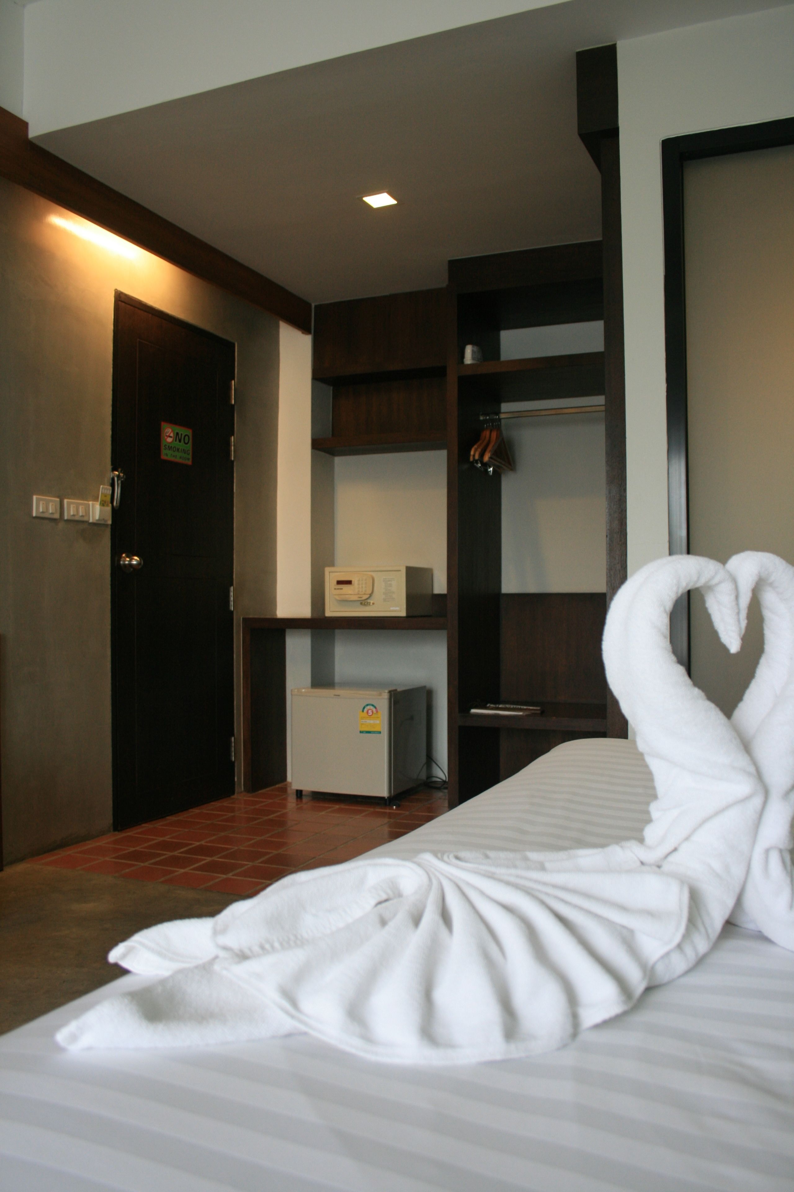 Habitación de hotel con cama, escritorio, refrigerador y armario.