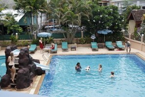 A swimming pool with rock formations, lounge chairs, and umbrellas. - BMP Residence (Chiang Mai)