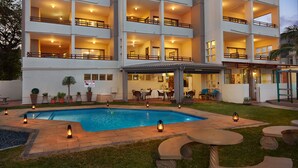 A multi-story hotel with a swimming pool, outdoor seating, and potted plants. - First Group Costa Smeralda (Margate)
