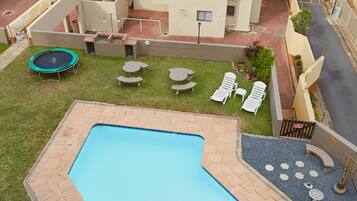 Piscina con vistas al océano, un trampolín y mobiliario exterior.