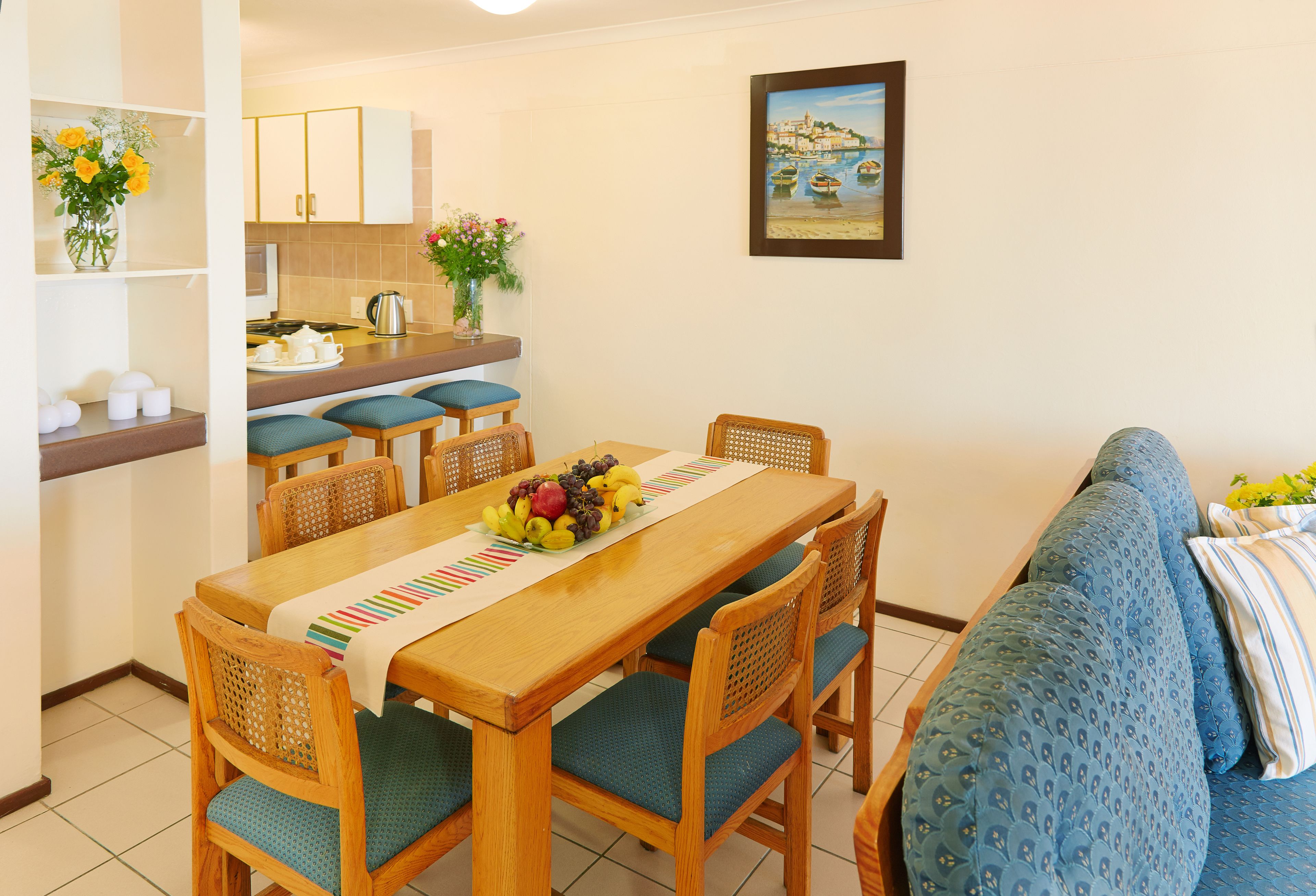 A dining area with a wooden table, chairs, and a blue sofa.