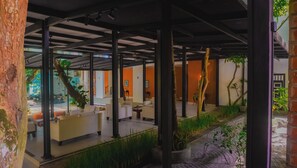 A covered outdoor seating area with modern furniture, potted plants, and a view of the street. - Clio Bolgoda (Piliyandala)