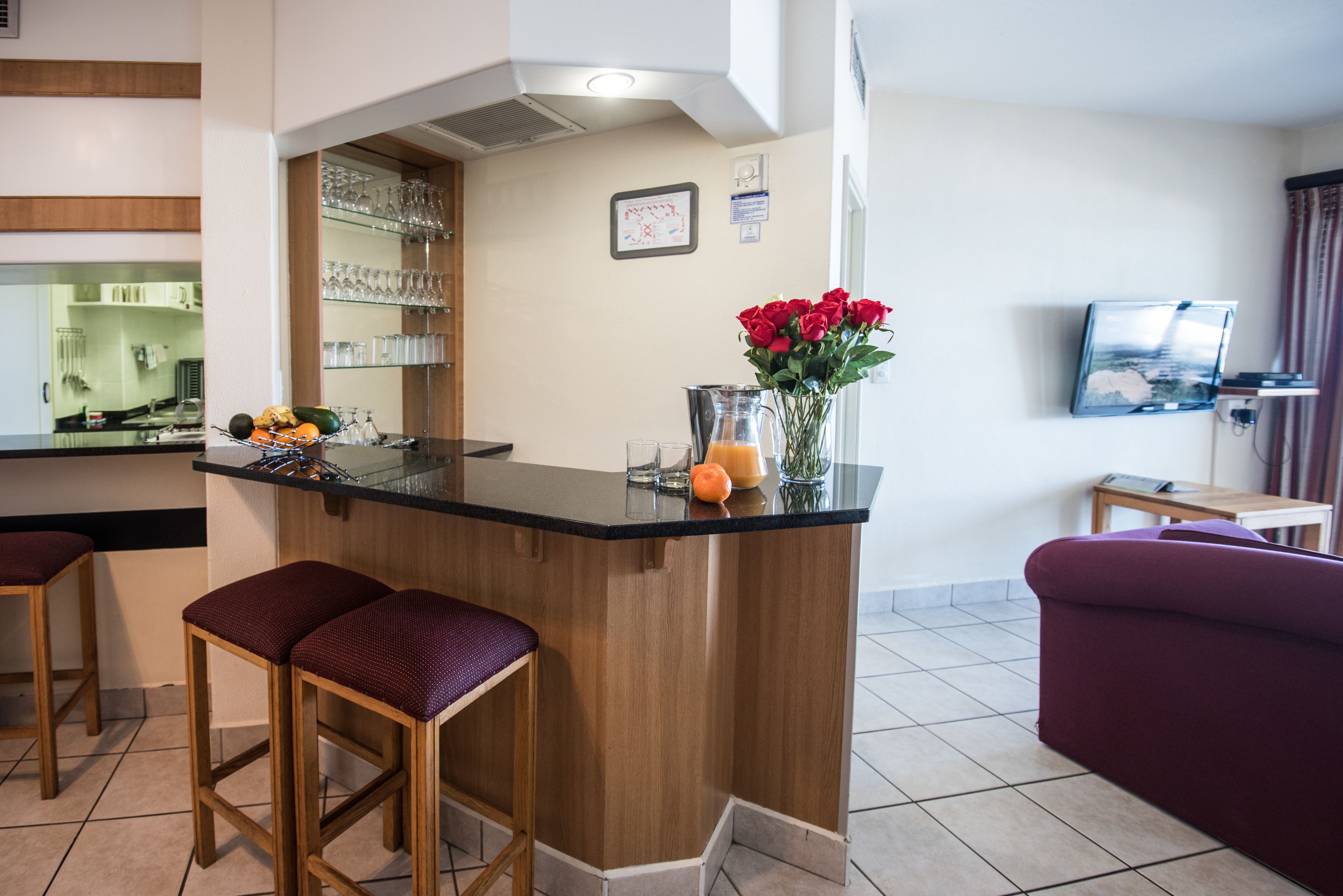 Una cocina moderna con barra, taburetes de madera y un florero con rosas rojas.