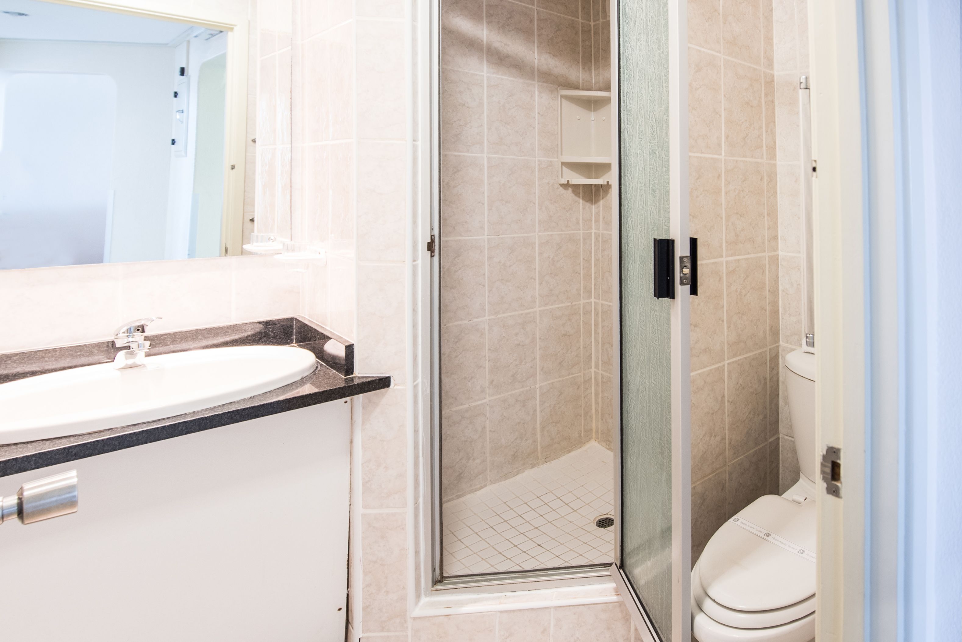Un baño con un lavamanos blanco, cabina de ducha de vidrio y un inodoro blanco.