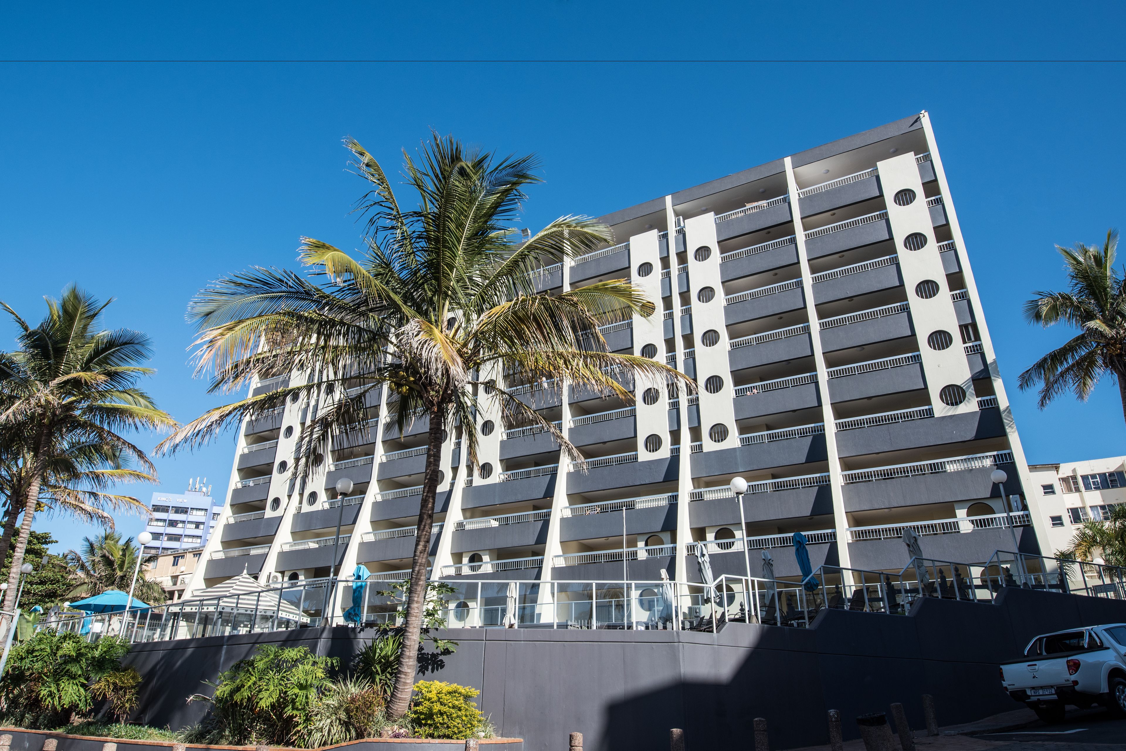 Een meerlaags parkeergarage met een modern design, voorzien van balkons en een heldere lucht.