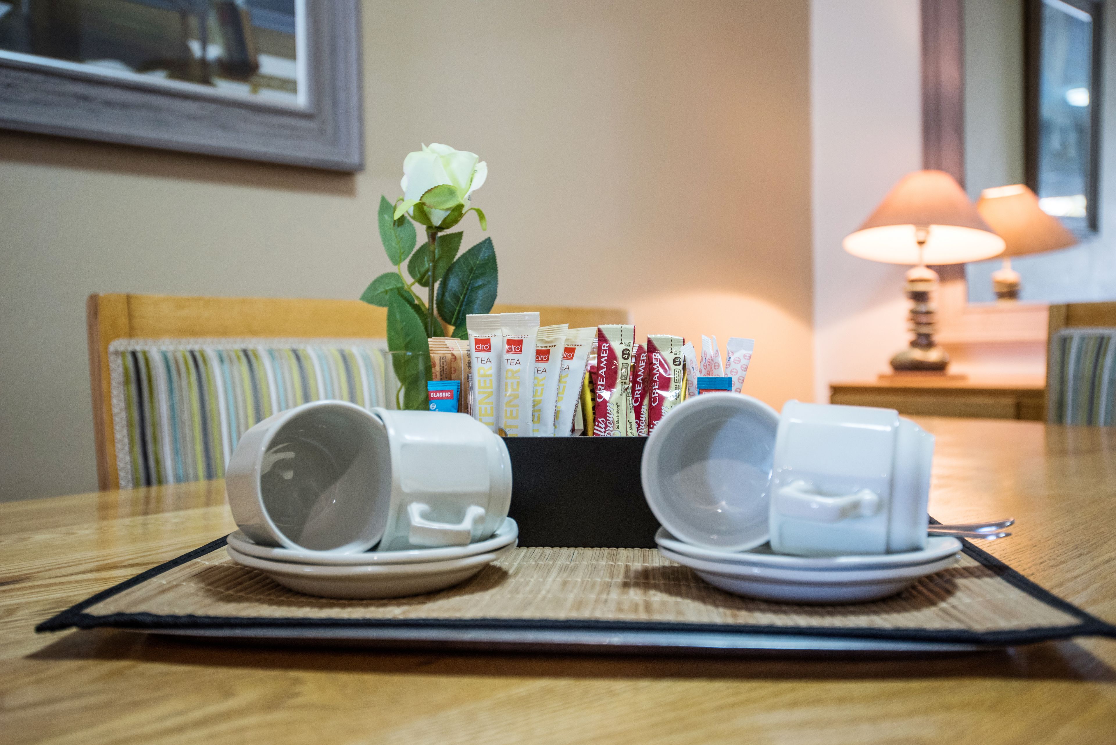 A table with a tea station, including tea packets and cups, in a hotel room.
