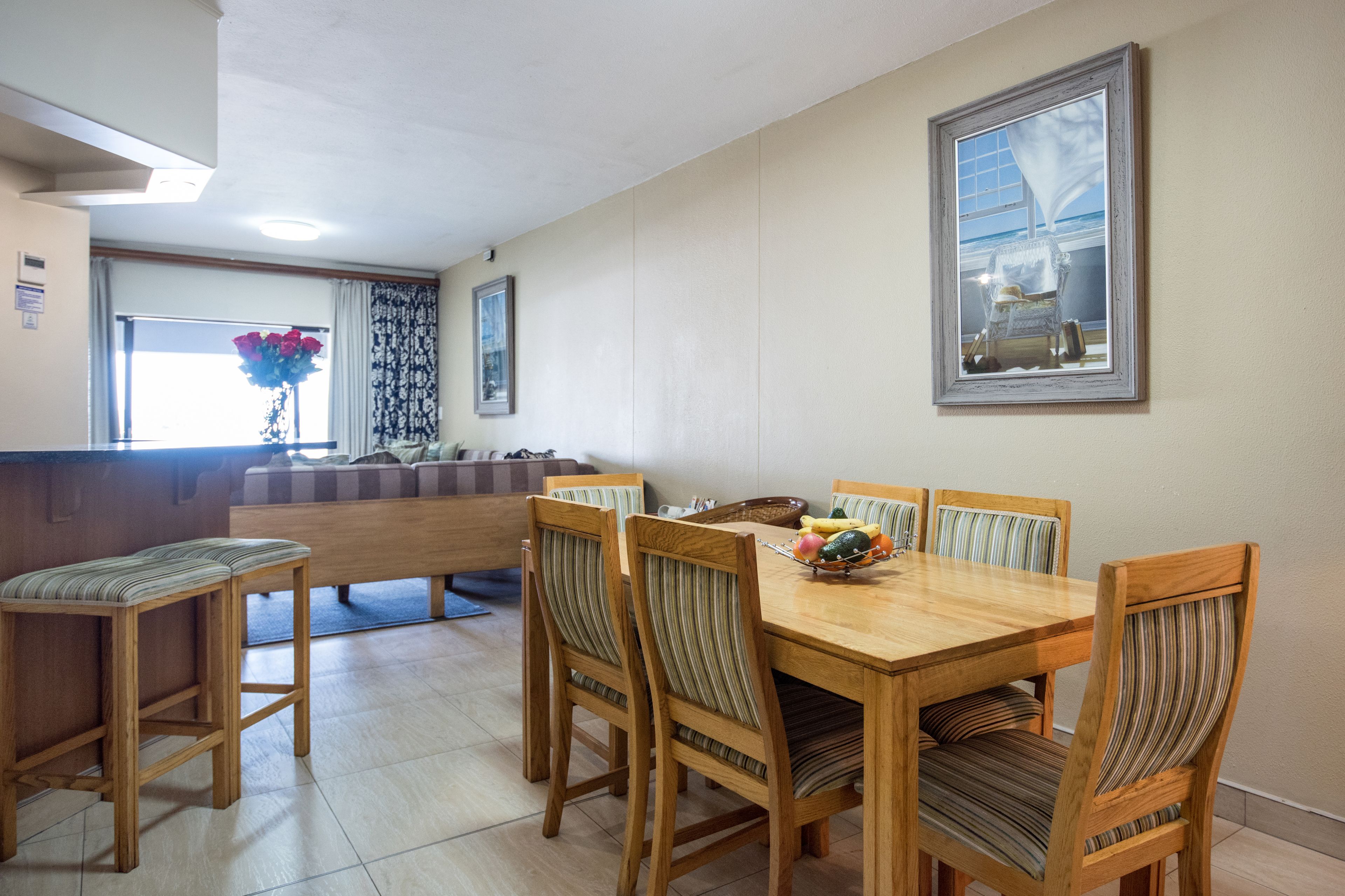 A dining area with a wooden table and chairs, a bench, and a window with curtains.