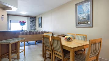 A dining area with a wooden table and chairs, a bench, and a window with curtains.