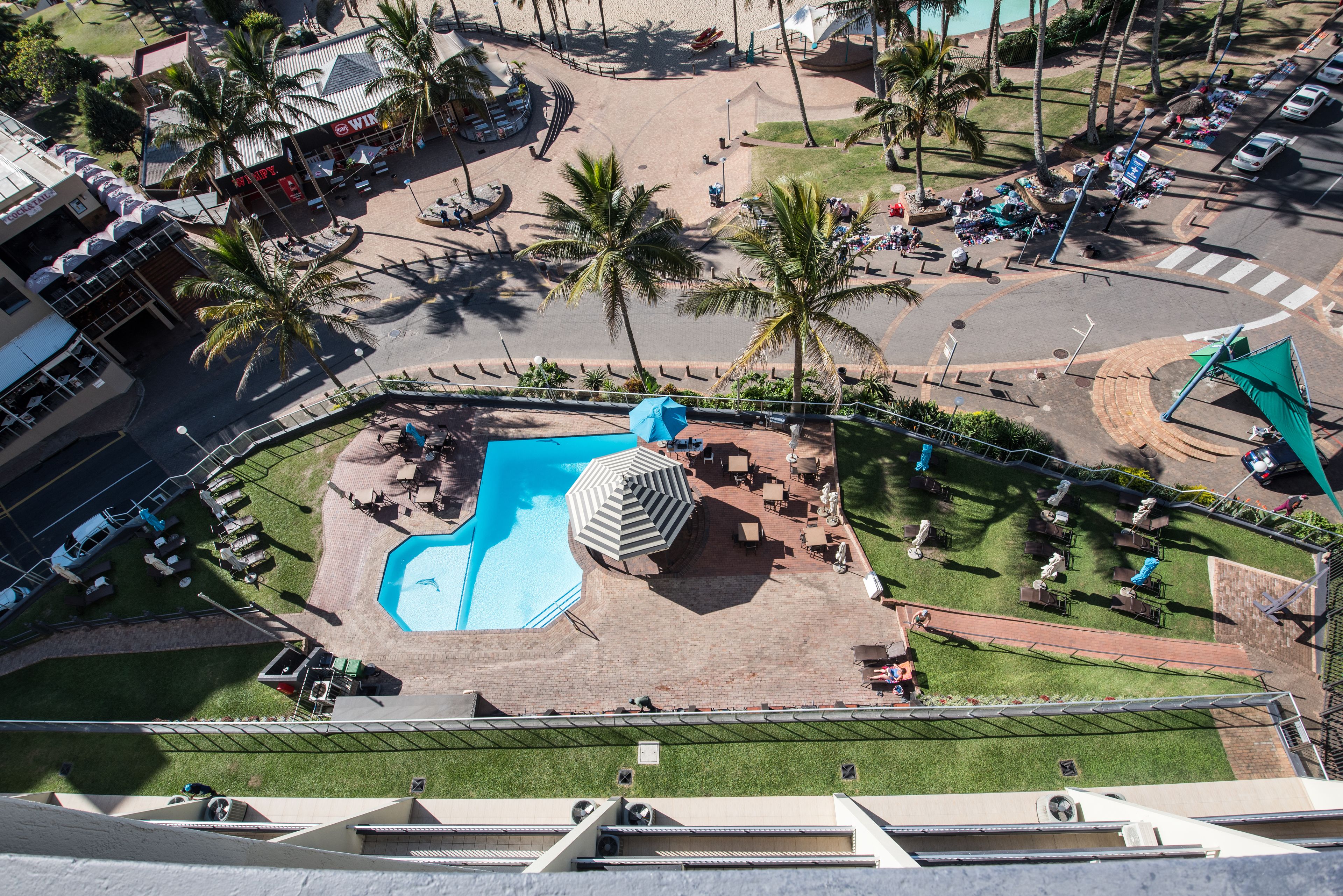 Un complexe hôtelier doté d’une piscine, de palmiers et d’espaces de détente en plein air.
