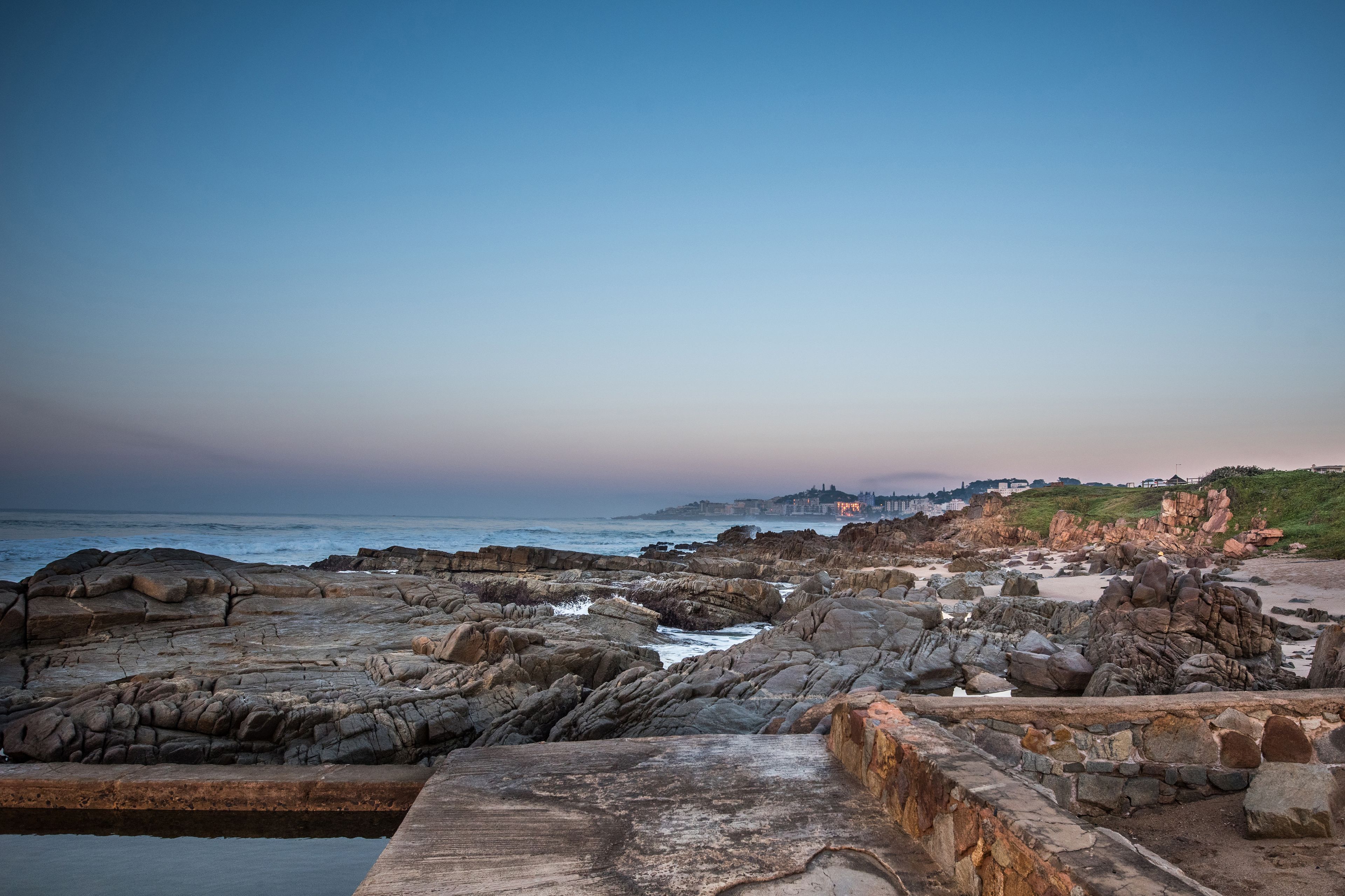 A rocky coastal landscape with a stone wall in the foreground.