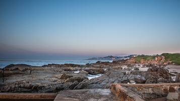 A rocky coastal landscape with a stone wall in the foreground.