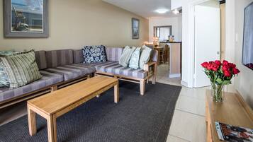 A living room with a sofa, a coffee table, and a dining area with chairs and a table.
