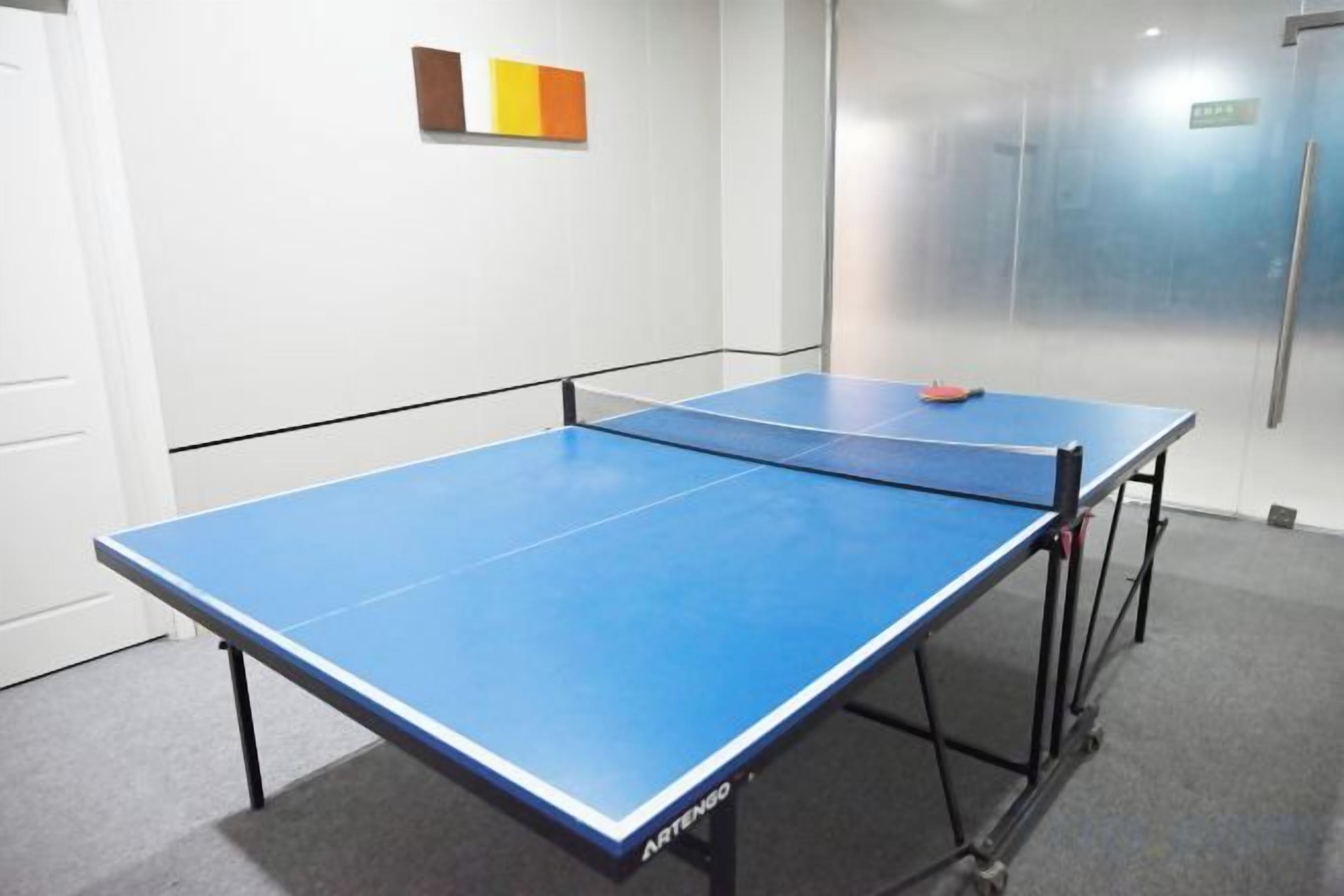 A ping pong table in a room with a white wall and a door in the background.