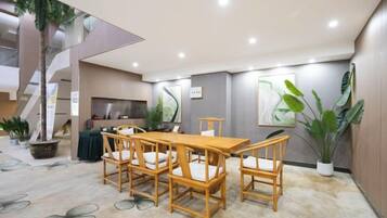 Un comedor con una mesa y sillas de madera, una escalera y una zona de cocina.