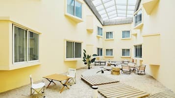 A spacious indoor courtyard with multiple seating areas, a central table, and a high ceiling with skylights.
