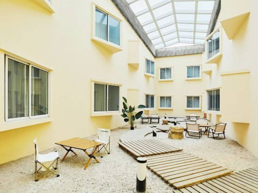 A spacious indoor courtyard with multiple seating areas, a central table, and a high ceiling with skylights.