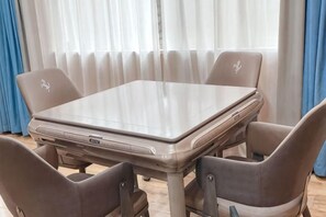 A dining table with four chairs, a laptop on the table, and a window with curtains. - Days Inn Frontier Wuxi (Wuxi)
