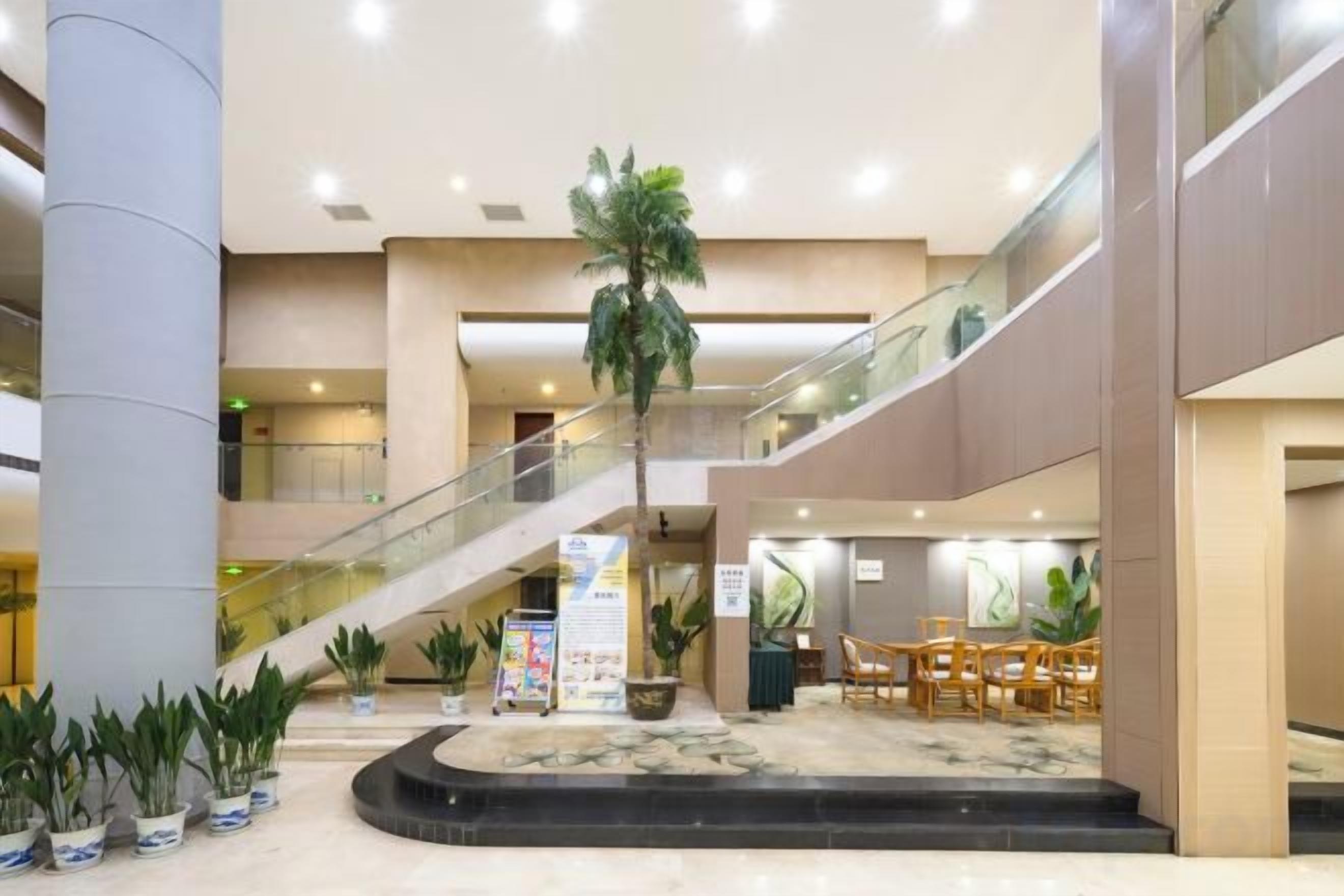 A multi-level atrium with a central staircase, potted plants, and seating areas.