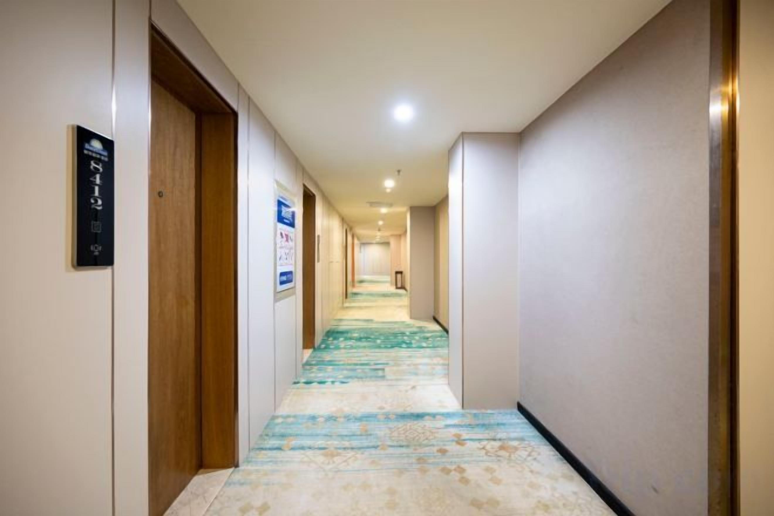 A hotel hallway with carpeted flooring, wooden doors, and a sign on the wall.