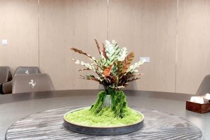 Et rundt bord med en blomsteropsætning, en vase og en servietæske.