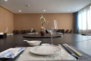 A conference room with a round table, chairs, a vase with flowers, and a glass on the table.