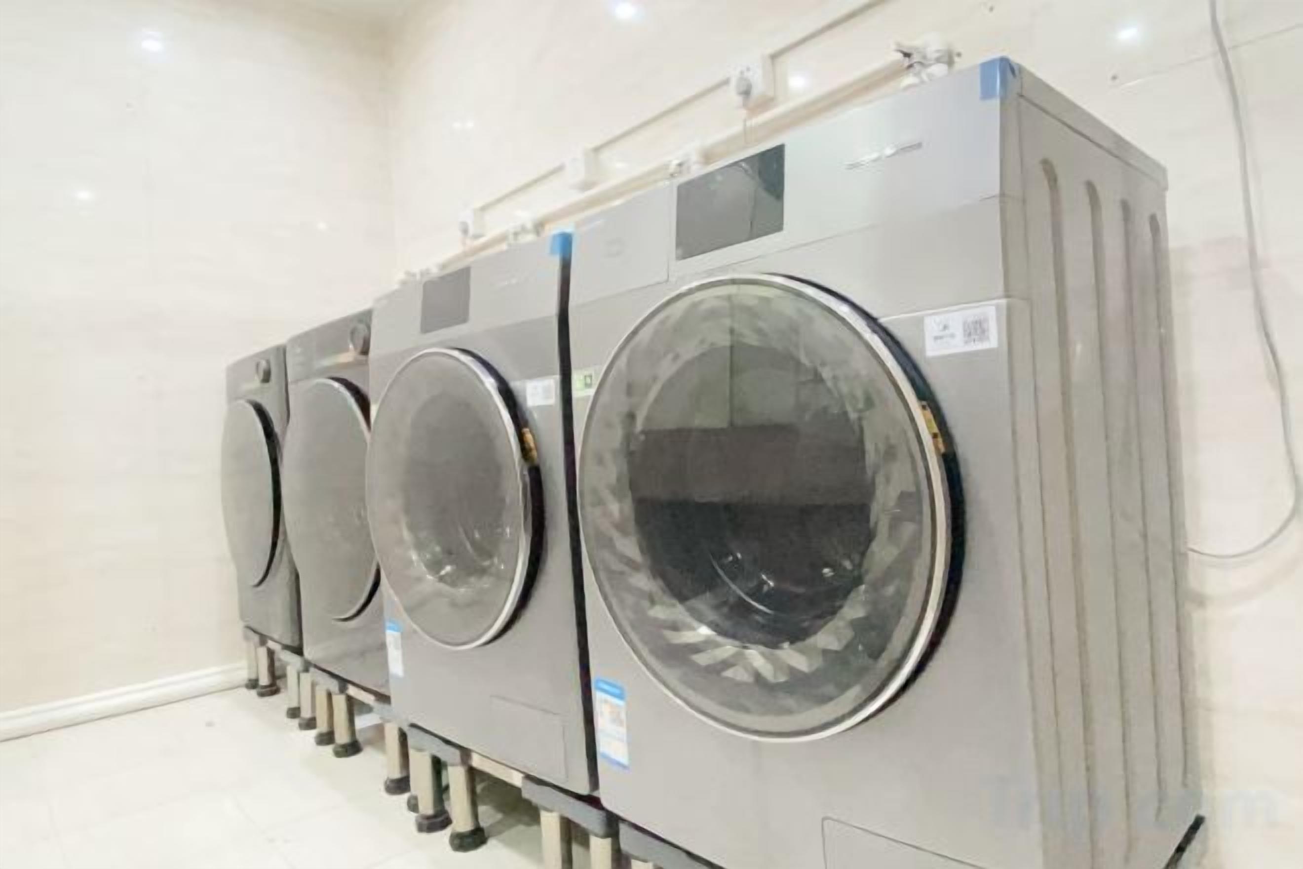 Varias lavadoras industriales apiladas en una habitación limpia con paredes blancas.
