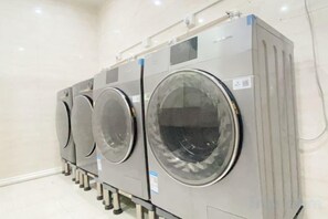 Varias lavadoras industriales apiladas en una habitación limpia con paredes blancas.